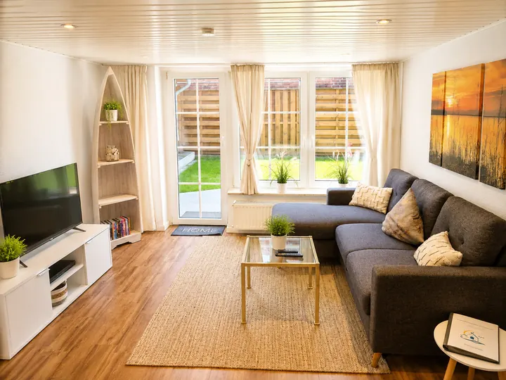 Helles Wohnzimmer mit Sofa und Zugang zum Garten