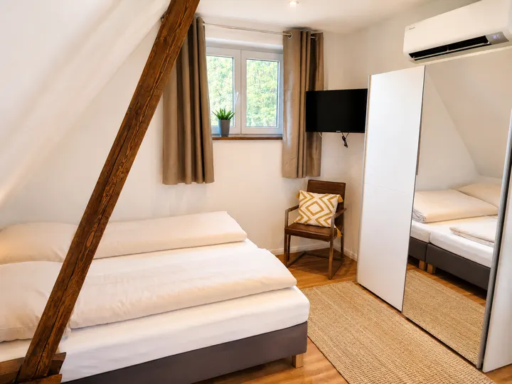 Schlafzimmer mit Betten, Fernseher und verspiegeltem Kleiderschrank