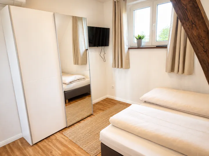 Schlafzimmer mit Doppelbett, Fernseher und Spiegelschrank