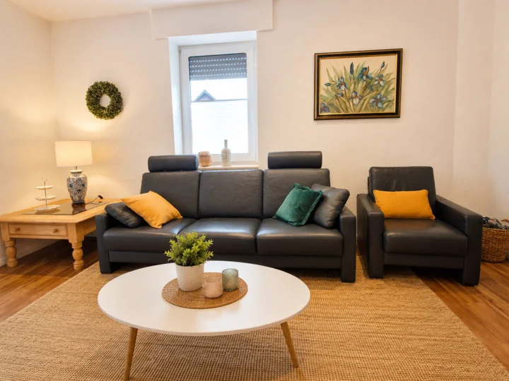 Gemütliches Wohnzimmer der Wohnung 5 mit Ledersofa und Sessel