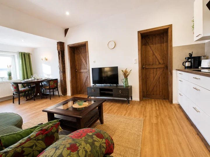 Wohnbereich der Wohnung 6 mit Fernseher, Couchtisch und Blick zum Essplatz