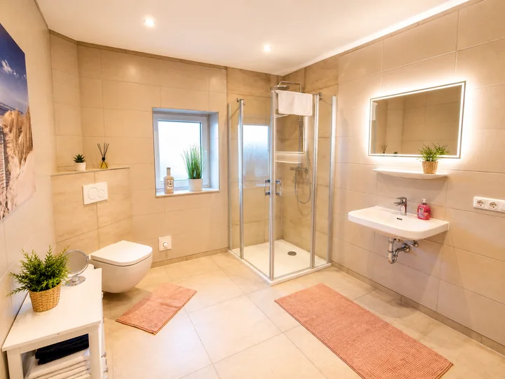 Großzügiges Badezimmer der Wohnung 6 mit Dusche, Waschbecken und beleuchtetem Spiegel